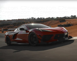 A red Corvette C8 on the road, fitted with a Legacy Edition front splitter and side canards for improved downforce.