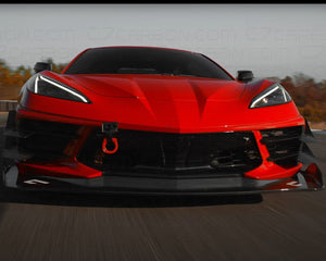 Front view of a red Corvette C8 Legacy Edition in motion on a racetrack.