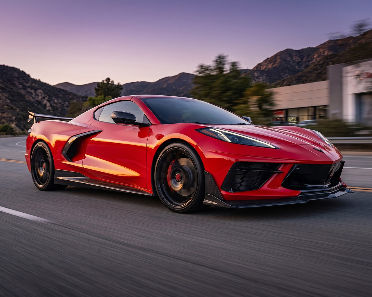 Red C8 Corvette driving on road equipped with low-drag Legacy Edition carbon rocker panel splitters