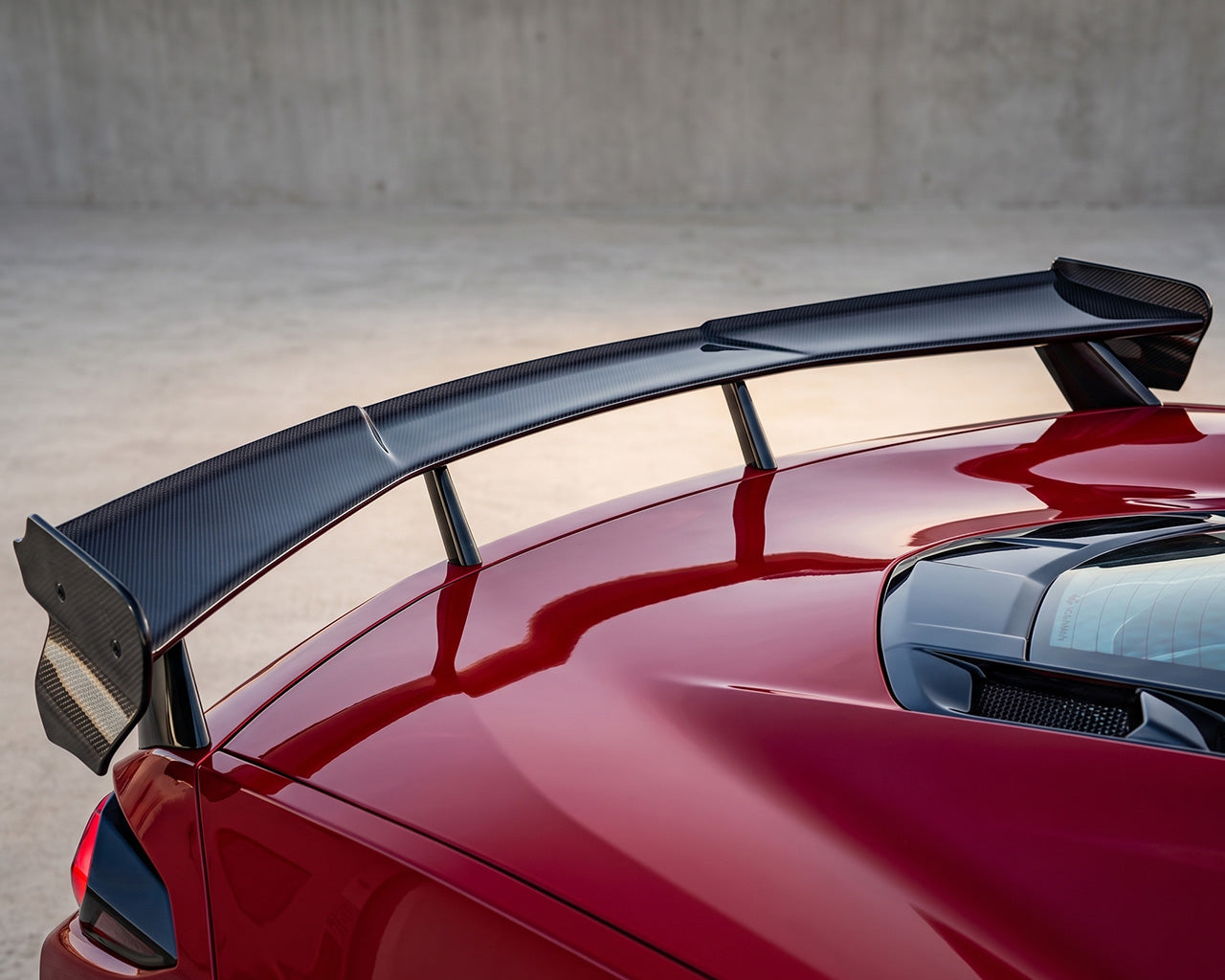 Close up view of c8 corvette stingray performance carbon fiber high wing spoiler on red C8 Corvette