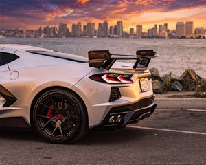 Silver C8 Corvette Stingray with Race Edition carbon fiber rear wing parked in front of city skyline