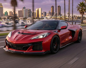 Front three quarter action shot of red C8 Corvette Z06 showing extended carbon fiber rocker panel extensions