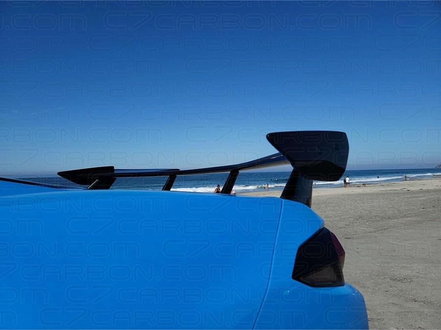 Close up view of pre-preg carbon fiber high wing upright and endplate on blue C8 Corvette