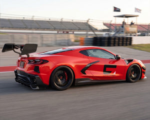 Rear three quarter track stance of red C8 Corvette showing CNC chassis uprights and Daytona wing blade