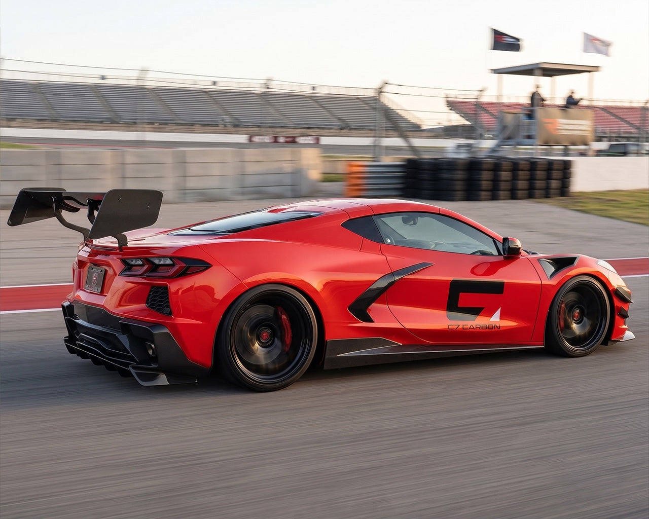 Rear three quarter track stance of red C8 Corvette showing CNC chassis uprights and Daytona wing blade