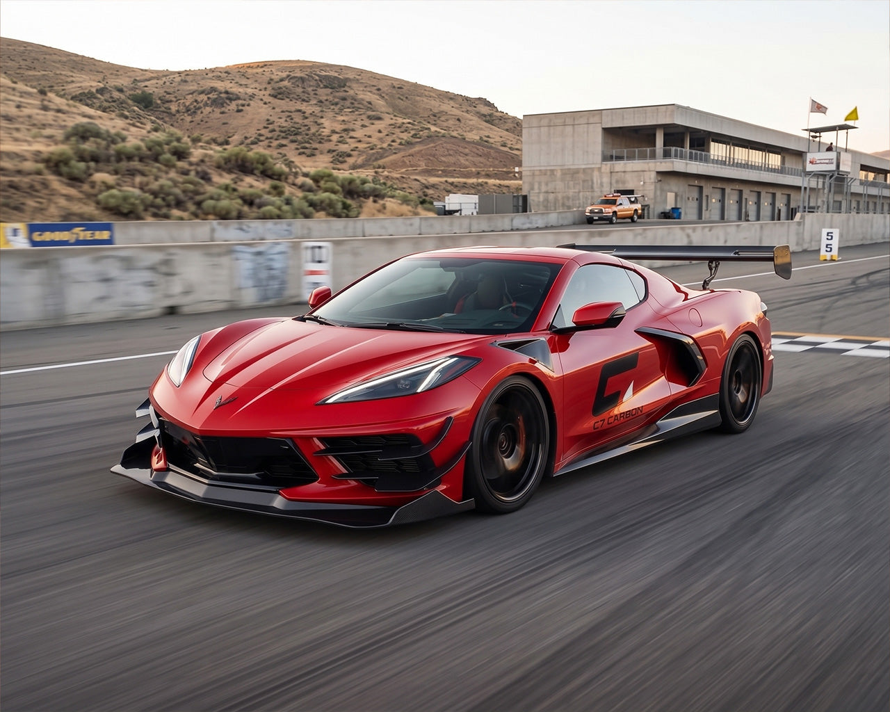 Front three quarter track view of red C8 Corvette Stingray equipped with carbon fiber Daytona race wing