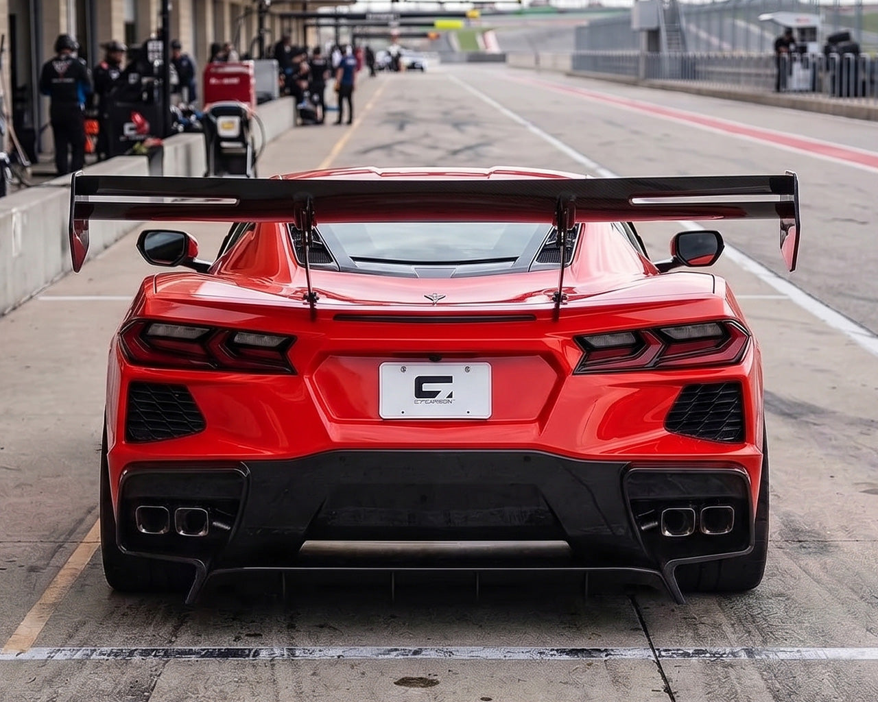 Direct rear view of red C8 Corvette in pit lane with Daytona chassis mounted carbon fiber track wing