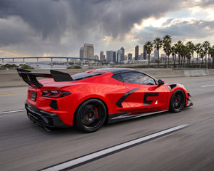 Side angle road view of red C8 Corvette Stingray featuring ZR1 carbon fiber high wing spoiler