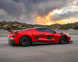 Full side profile stance of red C8 Corvette coupe equipped with ZR1 style carbon fiber rear wing