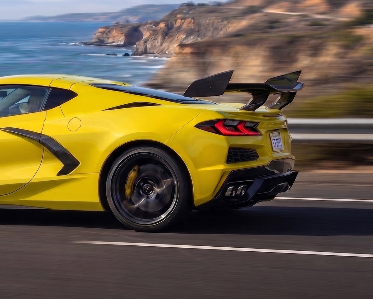 Coastal highway drive view of yellow C8 Corvette with pre-preg carbon fiber ZR1 high wing