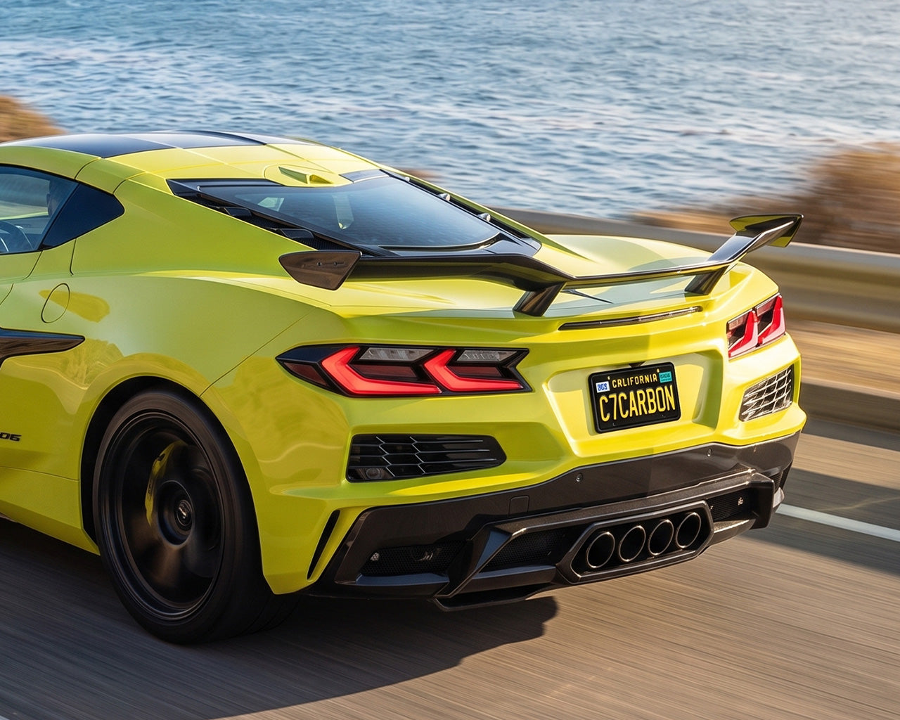 Yellow C8 Corvette Z06 driving on highway with carbon fiber Z07 high wing spoiler installed
