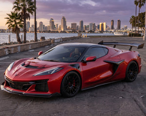 Low front three quarter view of red widebody C8 Corvette parked with full length carbon fiber side skirts