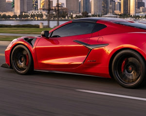 Full side profile driving shot of red widebody Corvette C8 Z06 equipped with full length extended carbon fiber side skirts