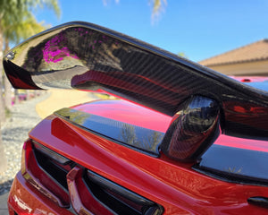 Carbon fiber rear bumper hole cover installed on red C8 Corvette Z06 with high wing spoiler