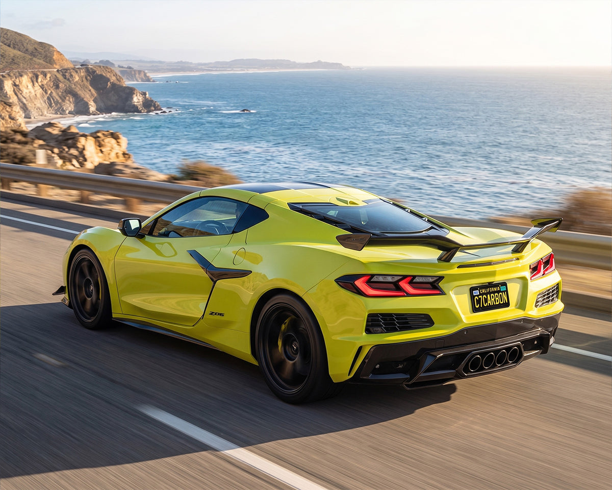 Yellow C8 Corvette Z06 cruising on coastal highway with carbon fiber Z07 high wing